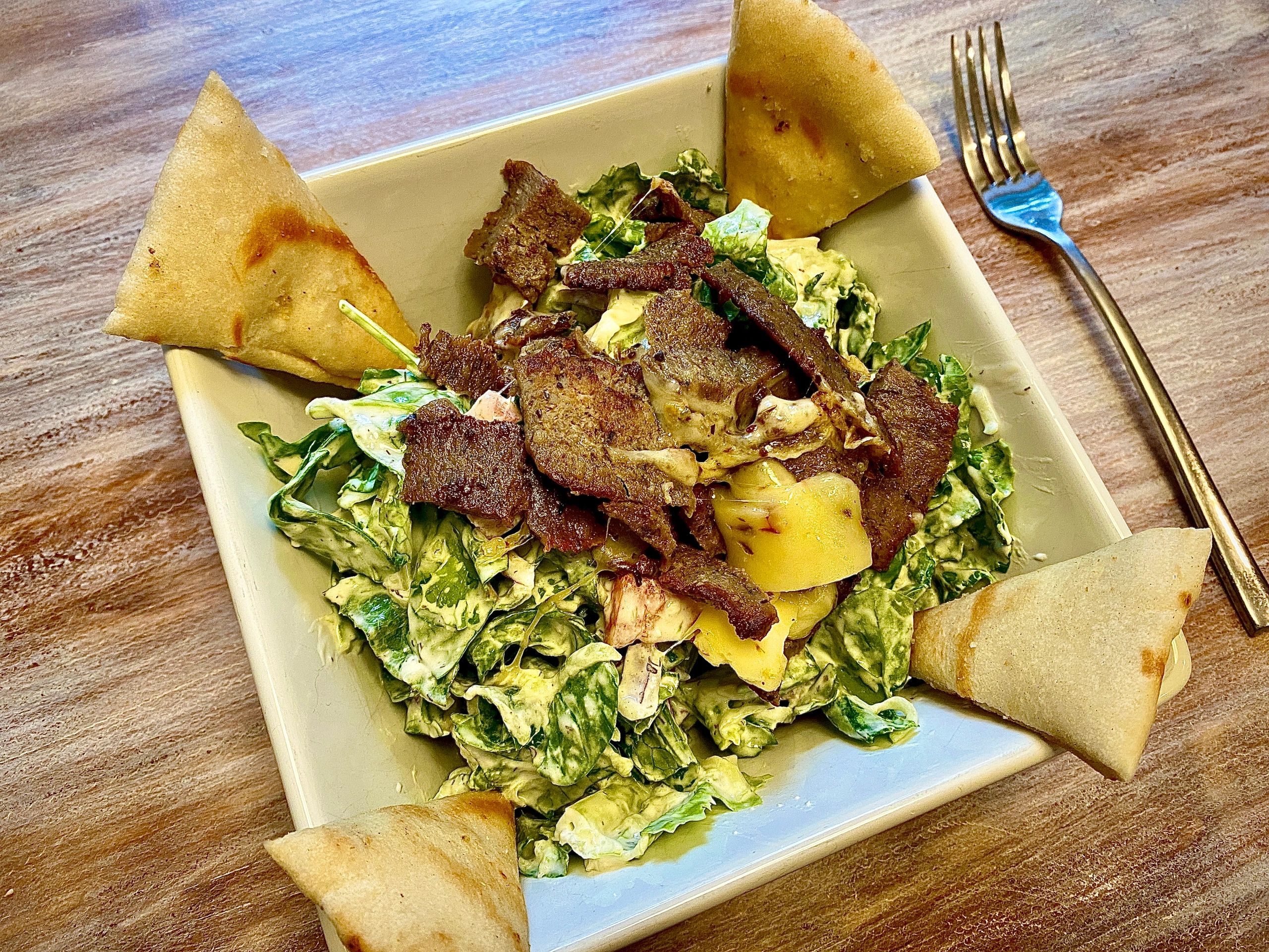 Large salad bowl with vegetables and pita wedges