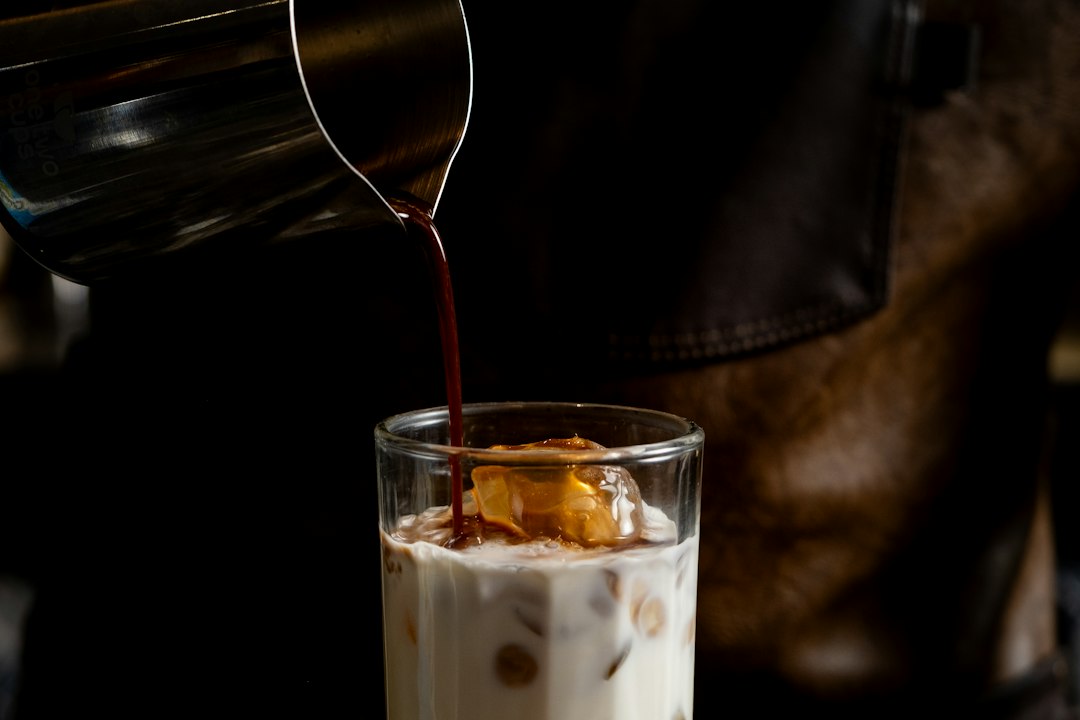 Coffee being poured into an iced milk drink for a homemade flavored latte