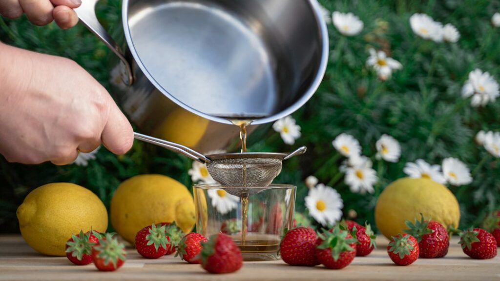Liquid being filtered through a fine mesh strainer during syrup preparation