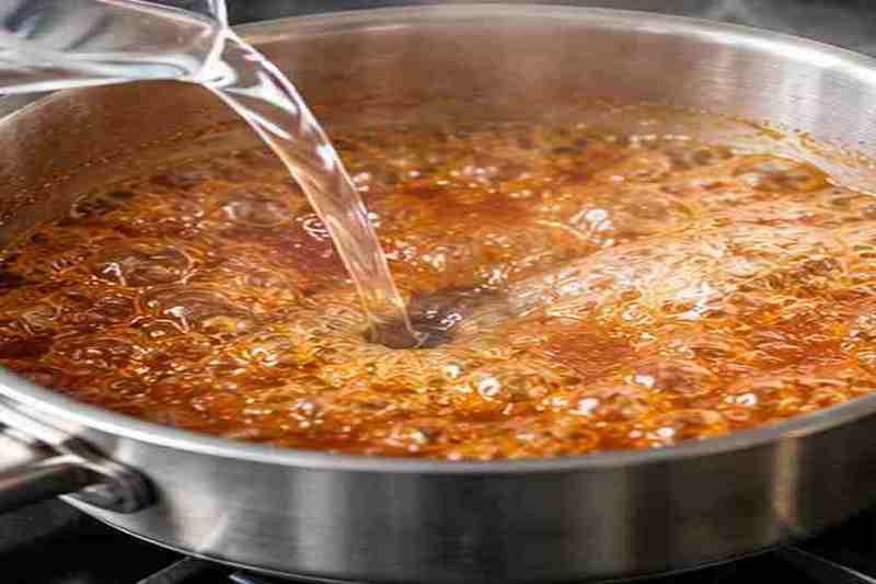 Caramel Syrup for Coffee: Easy Homemade Recipe 5 Hot water being added carefully to medium amber caramel syrup