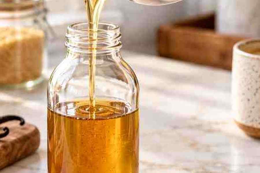 Caramel Syrup for Coffee: Easy Homemade Recipe 7 Homemade caramel syrup for coffee being poured into a clean glass bottle