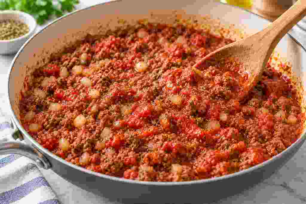 Ground beef filling simmering with crushed tomatoes and Italian seasoning for zucchini boats