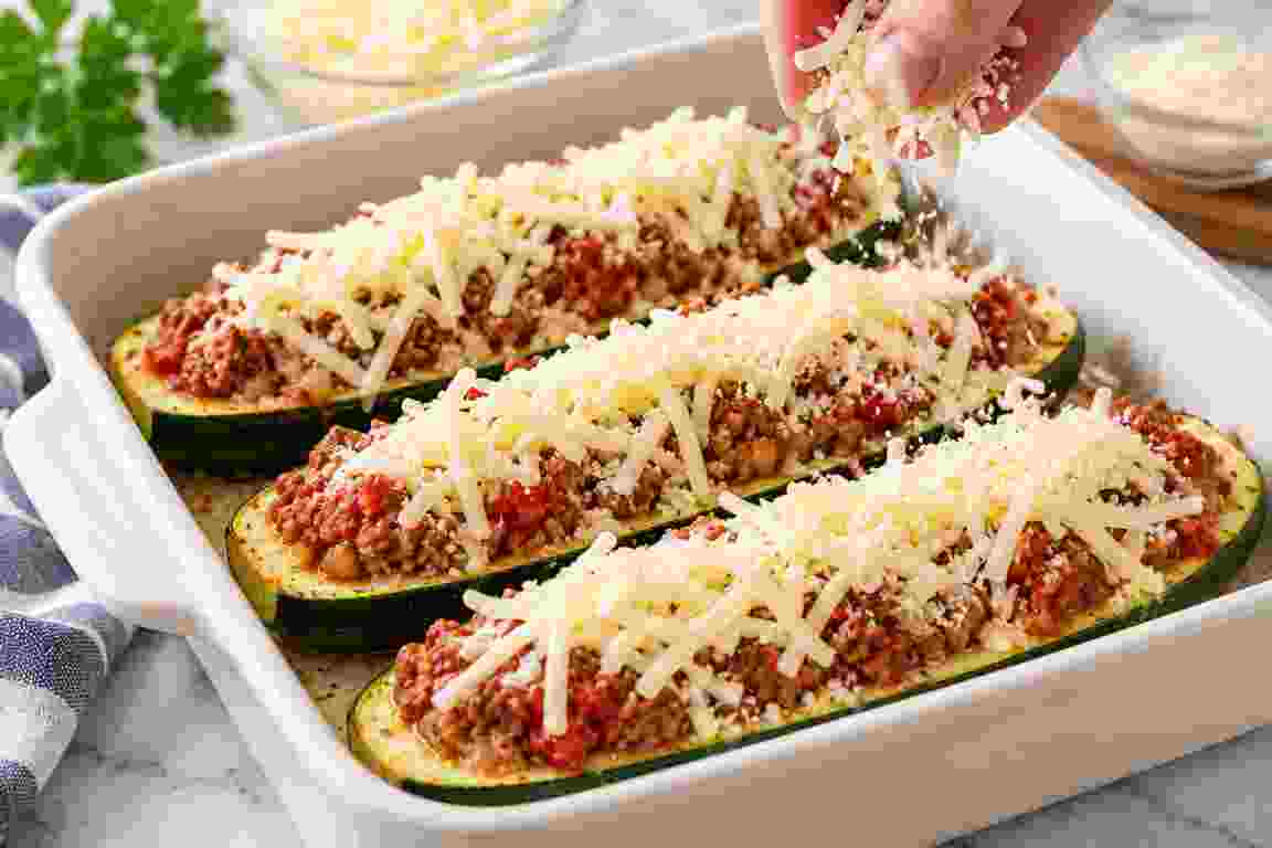 Stuffed zucchini boats topped with shredded mozzarella and grated Parmesan before baking