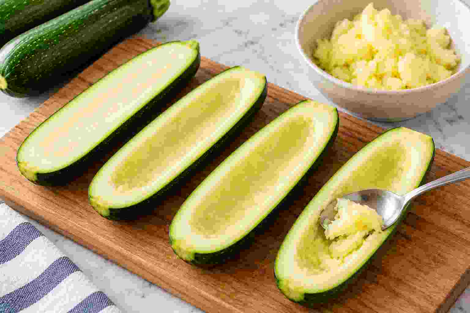 Zucchini halved lengthwise and centers scooped out to make stuffed zucchini boats